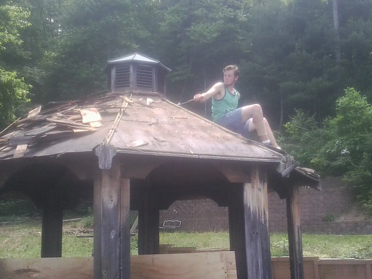 Tearing the old roof off a wooden gazebo before new shakes in Efland