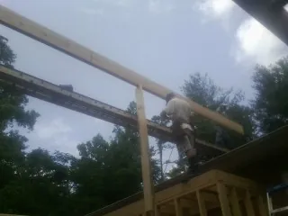 Carpenter setting a ridge beam over a new addition frame — Ice Dam Removal by Roofing Brothers in Efland