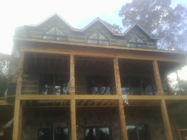 Dormers and porch framing on a large log home under construction — Roof Coating work by our crew in Efland