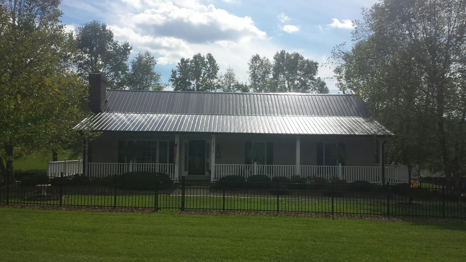 Gray metal roof on a brick ranch with a full width front porch — Gutter Guard Installation work by our crew in Efland