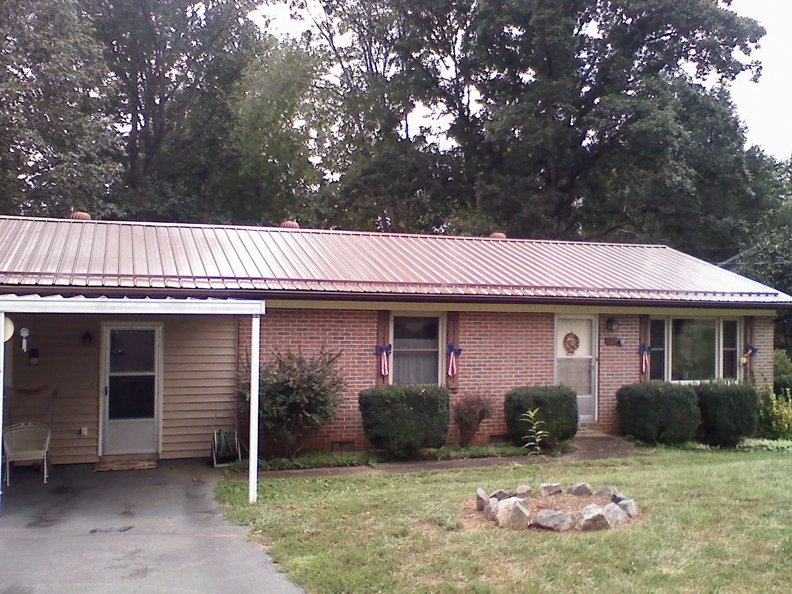 Bronze metal roof and carport on a brick ranch home — Roof Repair work by our crew in Efland