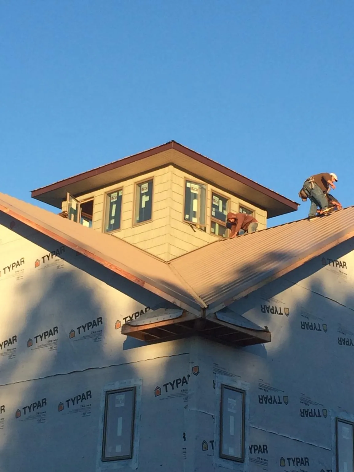 Roofers working around a rooftop cupola on a new metal roof at sunset — Roof Waterproofing in Efland by Roofing Brothers